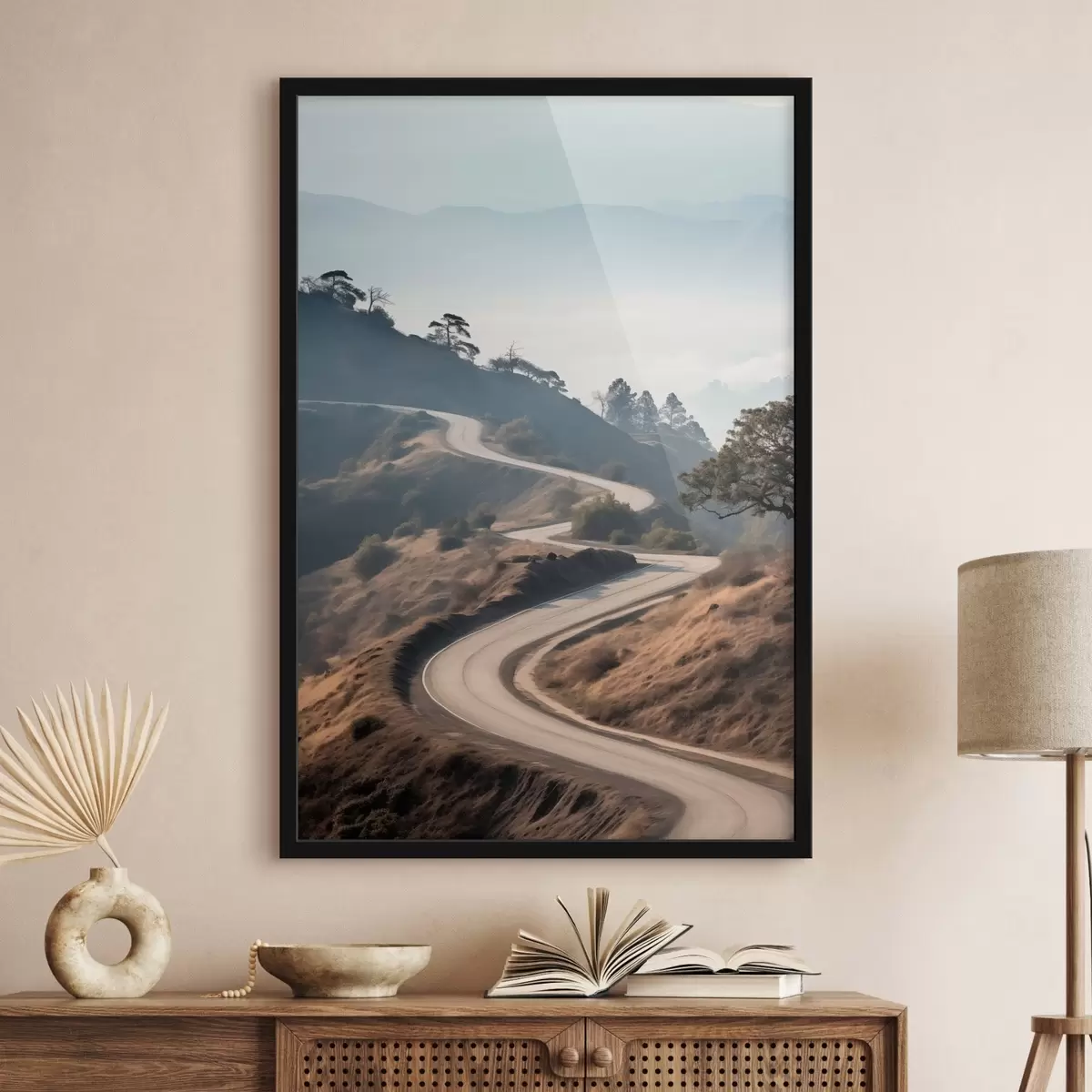 Poster Een kronkelende weg door een heuvelachtig landschap met droog gras onder een heldere hemel en bergen in de verte f46289